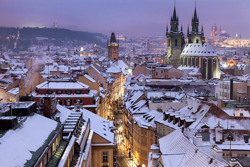 Panoramic view of castle, cathedral of Prague and historical buildings in old town of Prague, taken from one of the sides of Charles Bridge. There is a black street light standing at the bridge in the front and at the left side the famous John of Nepomuk Statue is standing.