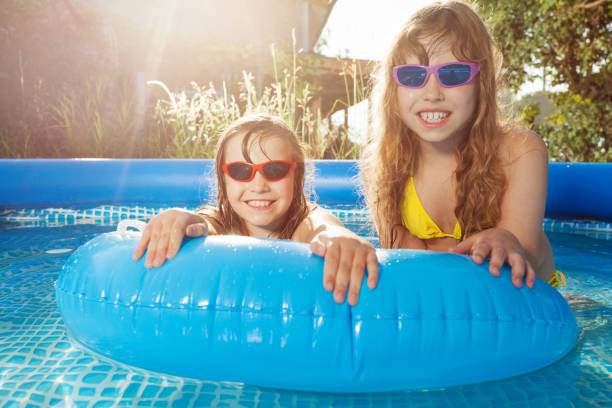istock Smiling girls swimming in pool with  rubber ring 647798634