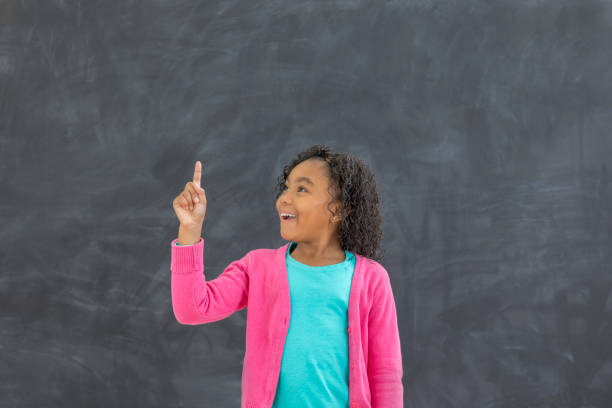 istock Young girl points to something on chalkboard 647798996