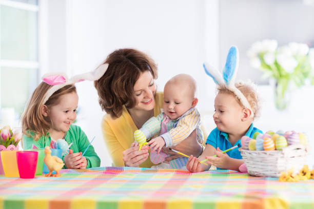 istock Mother with three children painting Easter eggs 647805682
