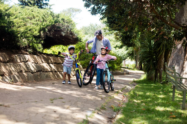 istock Father and children standing with bicycle in park 647808628