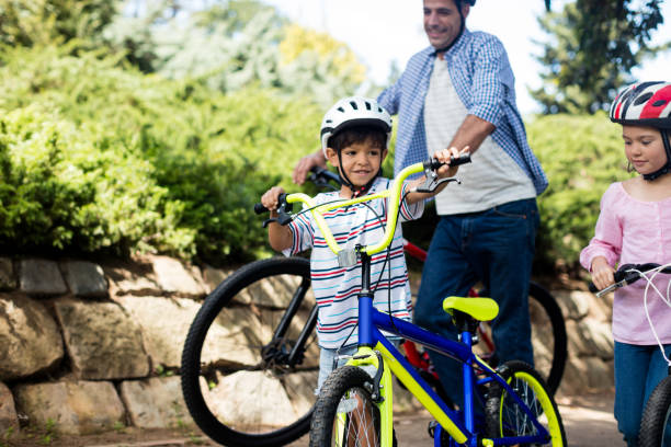 istock Father and children standing with bicycle in park 647809444