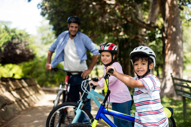 istock Father and children standing with bicycle in park 647809620