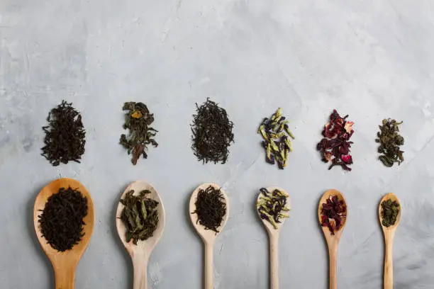 Wooden spoons with different tea leaves: black, white, blue, green, red (hibiscus) on 