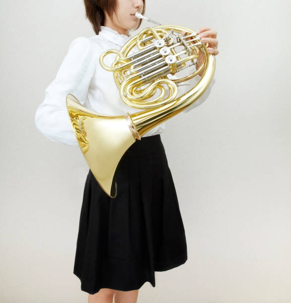 three musicians in a row playing the horn in a marching band at an outdoor parade, musician event
