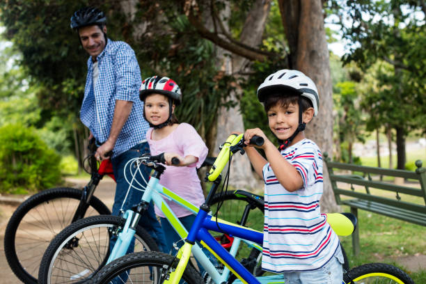 istock Father and children standing with bicycle in park 647819532