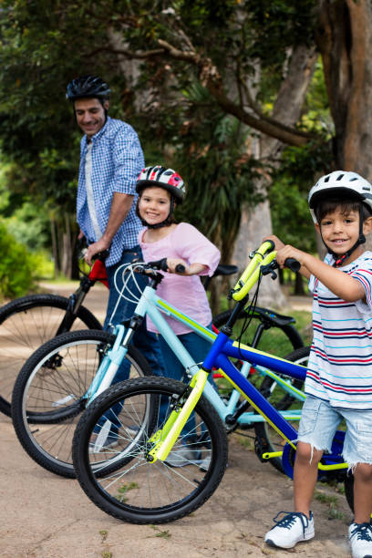 istock Father and children standing with bicycle in park 647819738