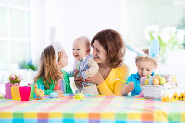 istock Mother with three children painting Easter eggs 647824332
