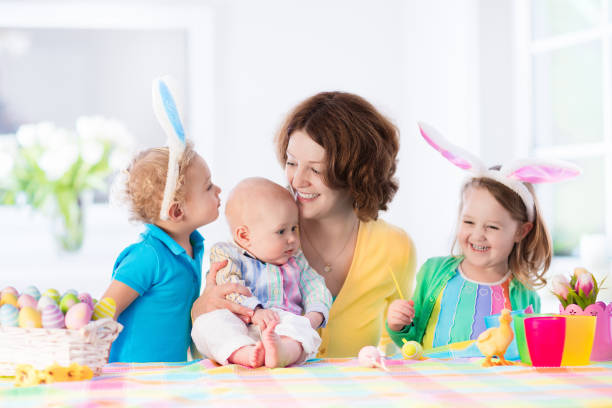 istock Mother with three children painting Easter eggs 647824586