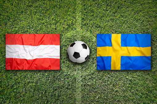 Austria vs. Sweden flags on green soccer field