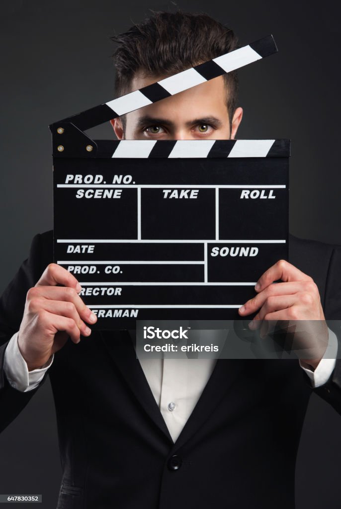 Business man holding a clapboard Studio portrait of a young man with a suit and holding a clapboard Actor Stock Photo