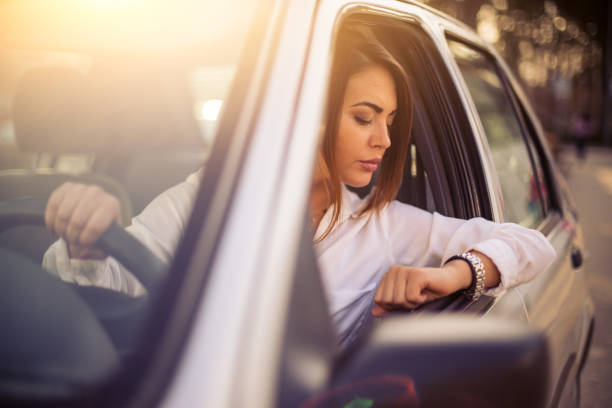 Beautiful businesswoman stuck into traffic, checking the time and being late