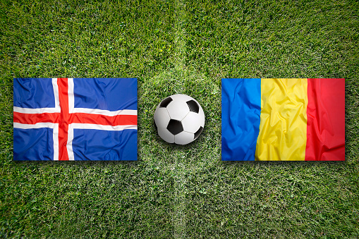 Iceland vs. Romania flags on green soccer field