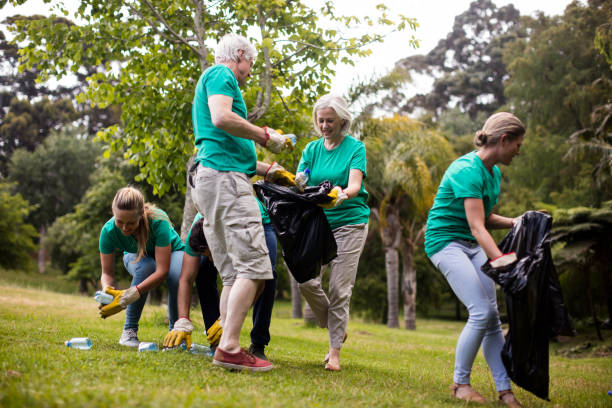 Team of volunteers picking up litter Team of volunteers picking up litter in park littering stock pictures, royalty-free photos & images