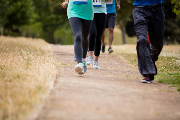 istock Low section of athletes running race in park 647858262