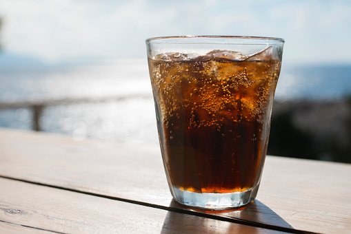 A glass of cola served with ice cubes.