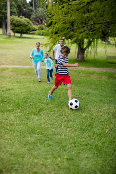 istock Happy family playing football in park 647956830