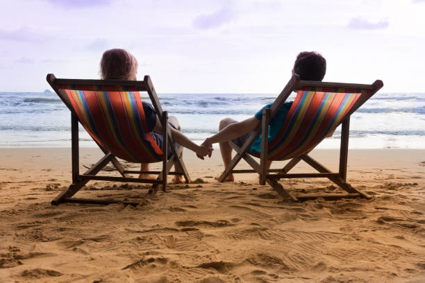 istock Romantic couple are sitting in deck chairs and holding their hands. 647957180