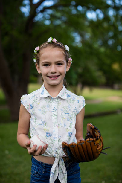 istock Cute girl holding baseball in park 647957606