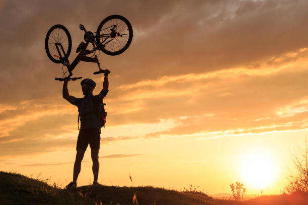 istock Biker lifting his bike on top mountain 647967860