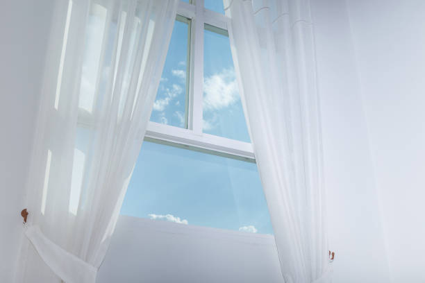 istock white curtain on the window with blue sky 647968094