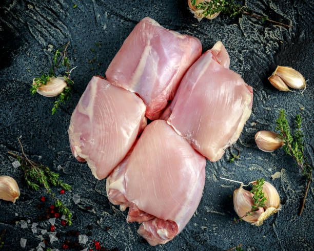 raw free range boneless skinless chicken thighs with thime, garlic, red pepper corns and sea salt flakes on stone table - chicken breast chicken grilled chicken protein imagens e fotografias de stock