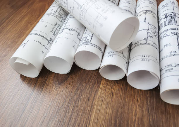 istock Architect workplace. Architectural project, blueprints, blueprint rolls on wooden desk table. Construction background. Engineering tools. Copy space 648005258