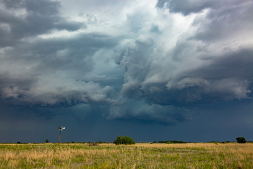 Old-style windmill dwarfed by severe, dangerous thunderstorm.  Horizontal, copy space.