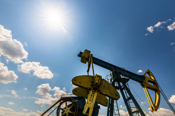 campo de petróleo com tomada de bomba, perfilado no céu azul com nuvens brancas, em um dia ensolarado - oil pump oil industry industry alberta - fotografias e filmes do acervo