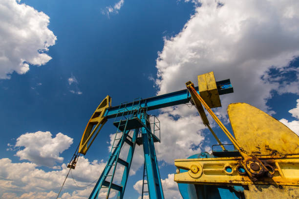 campo de petróleo com tomada de bomba, perfilado no céu azul com nuvens brancas, em um dia ensolarado - oil pump oil industry alberta equipment - fotografias e filmes do acervo