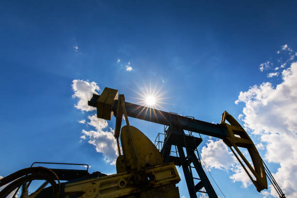 campo de petróleo com tomada de bomba, perfilado no céu azul com nuvens brancas, em um dia ensolarado - oil pump oil industry alberta equipment - fotografias e filmes do acervo