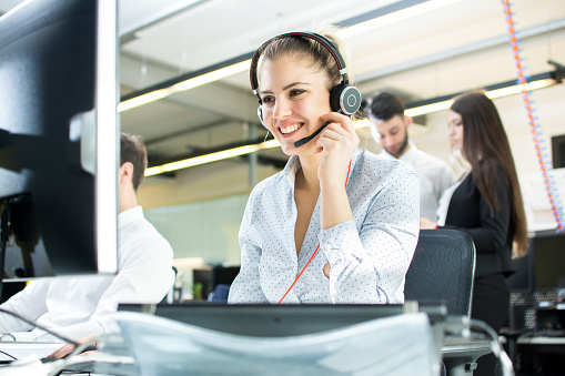 Sonriente mujer de agente con auriculares. Retrato del trabajador de centro de llamada en la oficina. photo