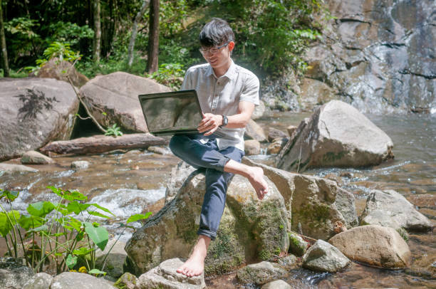 istock Traveller with backpack and laptop and phone at  waterfall  the forest. 648053706
