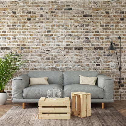 Modern gray sofa with  pillows in front of an empty brick wall. Square composition. interior template. designer copy space render with blank picture poster frame copy space. wooden coffee table, large plant and wall lamp.