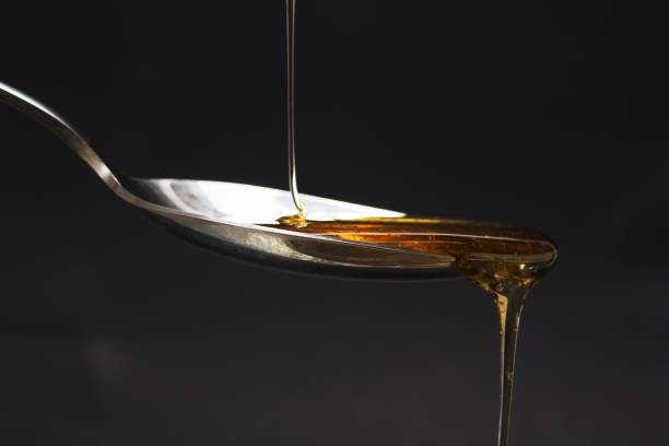 istock Honey pouring from spoon against a dark background 648081704
