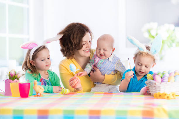 istock Mother with three children painting Easter eggs 648123440