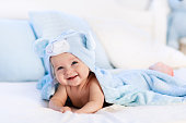 Baby in towel after bath in bed