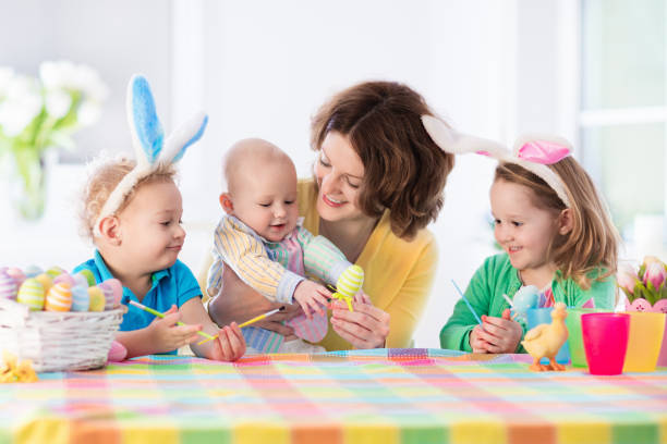 istock Mother with three children painting Easter eggs 648136438