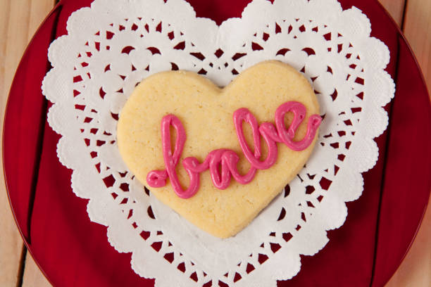 istock Heart shaped cookie iced with pink cream in text babe on wooden table 648136470