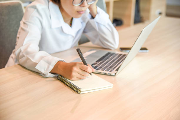 istock Businesswoman in workplace writing on notebook 648139776