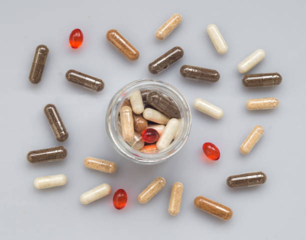 istock Different medicinal capsule spill out of a glass jar on a light 648179204