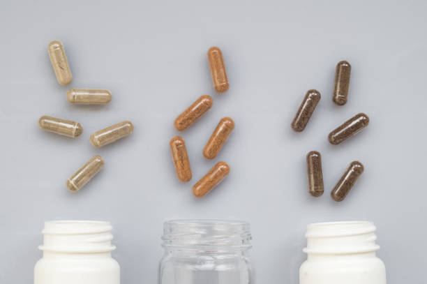 istock Medicinal capsule spill out of a three plastic bottles on a ligh 648179256