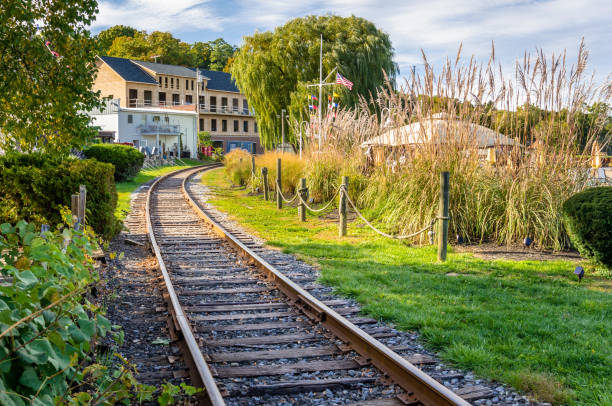 Empty Railroad Track through a Village Photo of a Curving Railway Track Running Through a Village on a Cloudy Fall Day. Two Buildings visible in background are very near the Track. watkins glen stock pictures, royalty-free photos & images