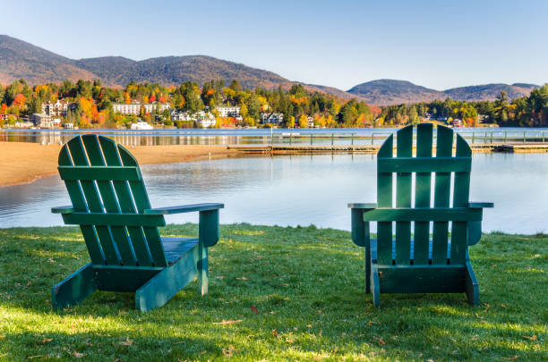 Adirondack Chairs on the Shore of Lake on a Clear Fall Morning Green Adirondack Chairs on the Shore of Mirror Lake in Lake Placid, Adirondack Mountains, NY, on a Clear Autumn Day mirror lake stock pictures, royalty-free photos & images