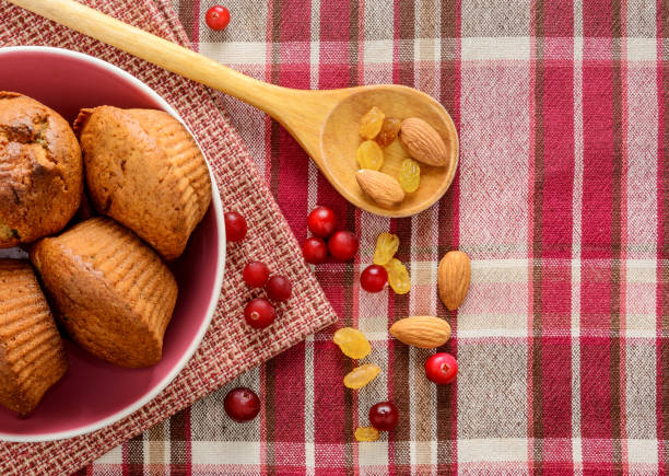 Freshly baked homemade muffins with cranberry raisins and nuts on napkin.