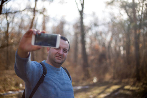 istock man in the woods makes selfie. Selfies time 648218046
