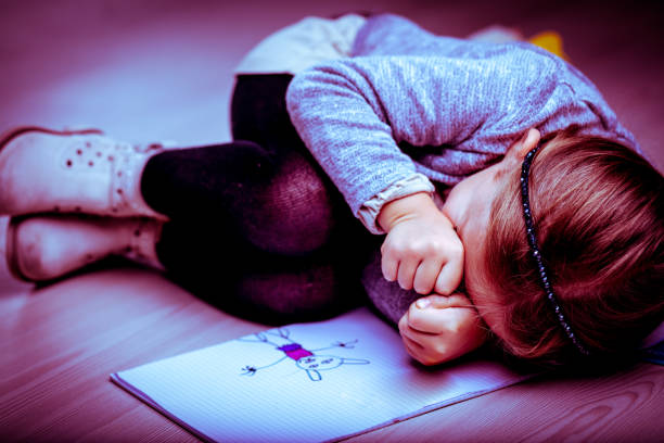 Upset little girl curled up next to her drawing Upset little girl curled up on the bed next to her drawing rubbing her eyes with her fists as though crying, side vignette batting sports activity photos stock pictures, royalty-free photos & images