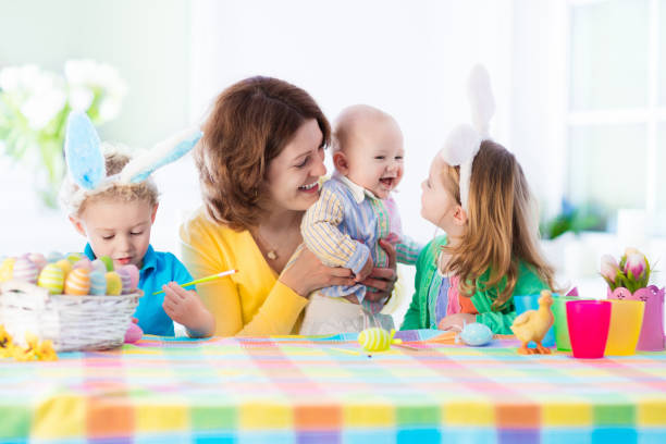 istock Mother with three children painting Easter eggs 648239858