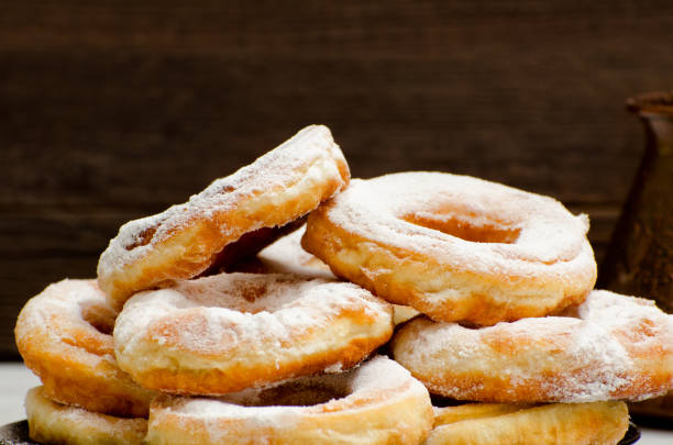 istock Donuts sprinkled with powdered sugar, dark wood background. Close-up, side view 648251626