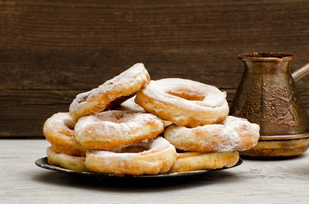 istock Donuts sprinkled with powdered sugar, coffee pots, dark wood background. Close-up, side view 648251714